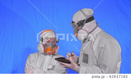 Scientist virologist in respirator makes write in an tablet computer with stylus. Man and woman wearing protective medical mask. Chroma key blue. 62637183