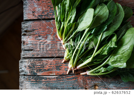 A bunch of young fresh juicy green spinach on a rustic wooden old-time red background. Flat lay A bunch of young fresh juicy green spinach on a rustic wooden old-time red background. Flat lay 62637652