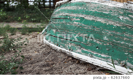 An old wooden green boat lies upside down on the shore. Close-up. An old wooden green boat lies upside down on the shore. Close-up. 62637660