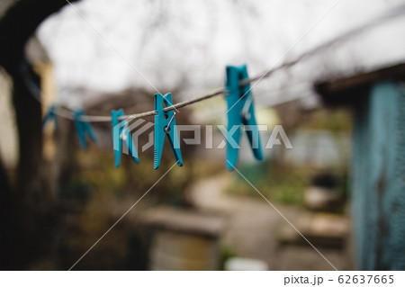 blue plastic clothespins on a clothesline on an autumn gloomy street. Perspective. Blur.Selective blue plastic clothespins on a clothesline on an autumn gloomy street. Perspective. Blur.Selective 62637665