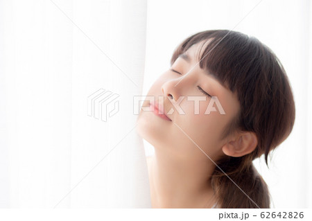 Portrait of beautiful young asian woman standing the window and smile while wake up Portrait of beautiful young asian woman standing the window and smile while wake up 62642826