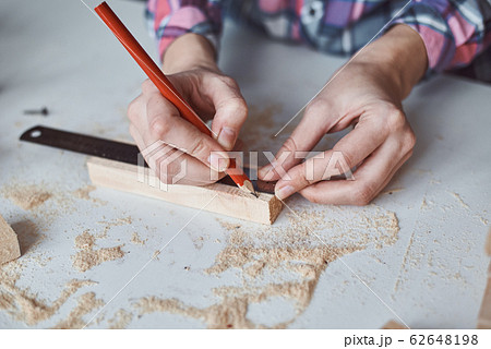 Carpenter hands taking measurement with a pencil 62648198