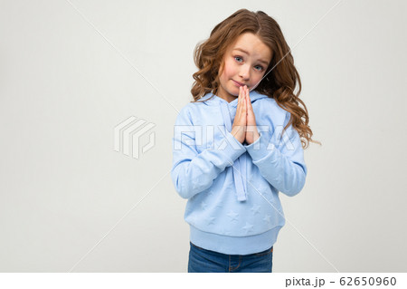 cute teenage girl in a blue hoodie prays to buy something on a light gray background cute teenage girl in a blue hoodie prays to buy something on a light gray background 62650960