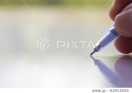 Woman's right Hand holding   transparent plastic ballpoint pen, Writing letter on white acrylic background, Close up & Macro shot, Selective focus, Communication, Business, Education, Stationery conce 62653850