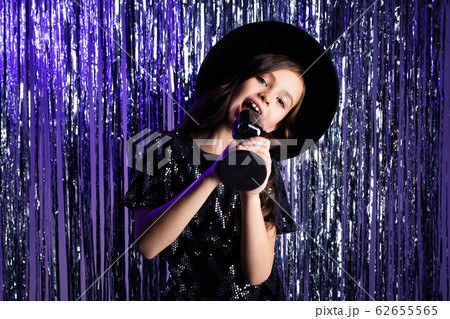 young fashionista in a black hat with fields with a microphone in her hands at a party against a 62655565