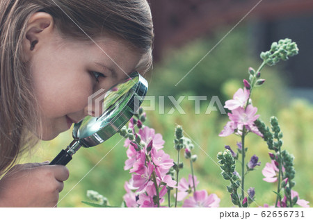 Curious girl exploring flowers with magnifying 62656731
