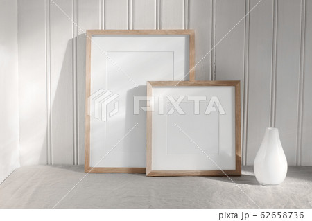 Two portrait and square wooden frame mockups. Linen cloth and modern ceramic vase with in sunlight. White beadboard wainscot wall paneling background. Scandinavian interior, home design. Art concept. Two portrait and square wooden frame mockups. Linen cloth and modern ceramic vase with in sunlight. White beadboard wainscot wall paneling background. Scandinavian interior, home design. Art concept. 62658736