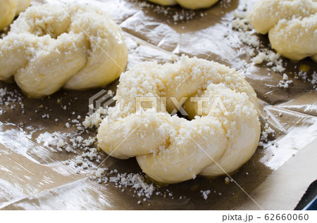 Preparation process - raw unbaked buns. Ready to bake homemade traditional buns on baking paper. Preparation process - raw unbaked buns. Ready to bake homemade traditional buns on baking paper. 62660060