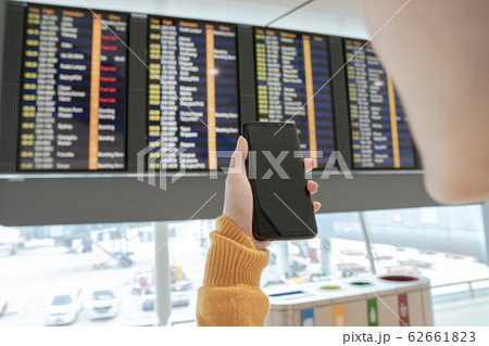 Young woman checking flight on timetable 62661823