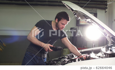 Young Technician Man Making Engine Service of Car in Garage. Young Technician Man Making Engine Service of Car in Garage. 62664046