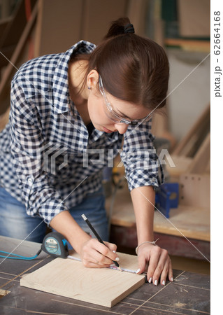 Young carpenter woman in glasses with tape measure and blackboard 62664168
