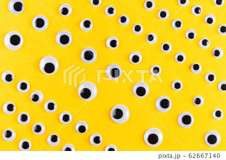 Googly plastic eyes pattern on yellow backgroud. Googly plastic eyes pattern on yellow backgroud. 62667140