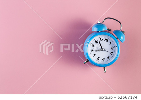 Blue vintage alarm clock on light pink color Blue vintage alarm clock on light pink color 62667174