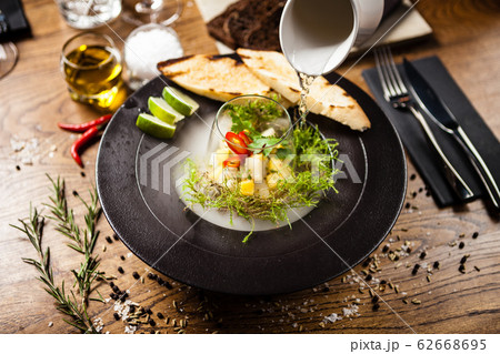 Scallop ceviche served in black bowl with liquid ice smoke 62668695