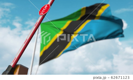 Opening boom barrier with stop sign against the Tanzanian flag. Free border crossing or lifting a ban in Tanzania. 3D rendering 62671123