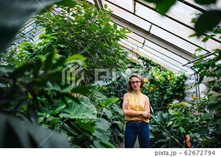 Young woman standing in greenhouse in botanical garden. Copy space. 62672794