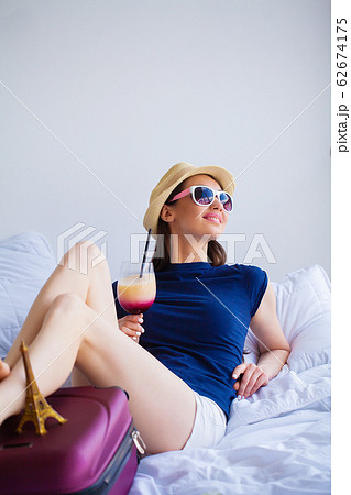 Vacation. Woman Who is Preparing for Rest. Young Beautiful Girl Sits on the Bed. Portrait of a Smiling Woman. Happy Girl Goes On Vacation Vacation. Woman Who is Preparing for Rest. Young Beautiful Girl Sits on the Bed. Portrait of a Smiling Woman. Happy Girl Goes On Vacation 62674175