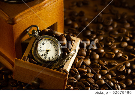 Coffee bean and pocket watch the tray of manual grinder on table. Concept of coffee time in morning. Coffee bean and pocket watch the tray of manual grinder on table. Concept of coffee time in morning. 62679496