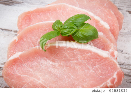 Slices of fresh loin with basil for cooking 62681335