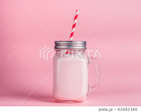 strawberry smoothie in mason jar glass on pink strawberry smoothie in mason jar glass on pink 62682360