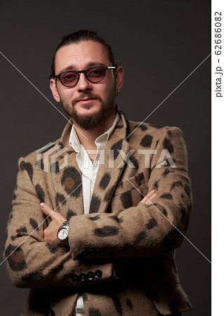 Male in sunglasses in jacket with arms crossed on brown background 62686082