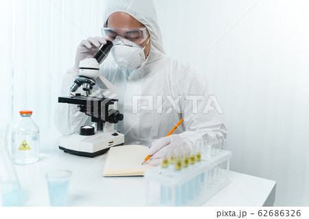 Competent scientist making notes during diagnostic of COVID-19 62686326