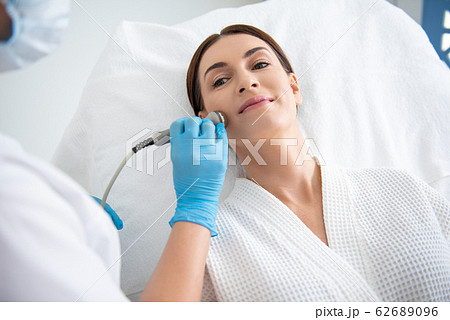 Young lady having face roll massage procedure 62689096
