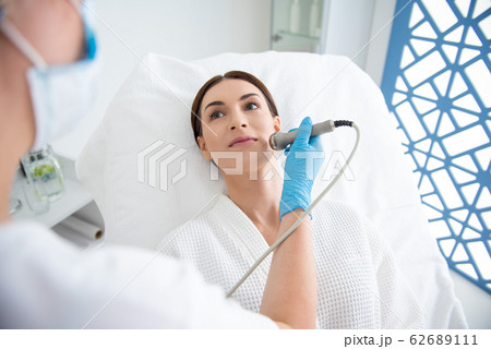 Lady enjoying of face roll massage procedure 62689111