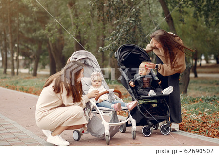 Two young mothers walking in a autumn park with carriages 62690502