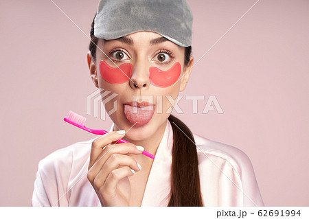 Charming young woman with under-eyes patches showing her tongue Charming young woman with under-eyes patches showing her tongue 62691994