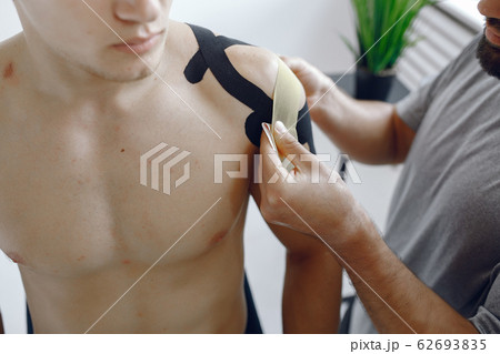 Doctor glues a tepee to an athlete at the hospital Doctor glues a tepee to an athlete at the hospital 62693835