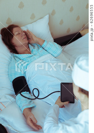 Doctor checking sick elderly woman at home. Medical help for pensioner, volunteer. Doctor checking sick elderly woman at home. Medical help for pensioner, volunteer. 62696555