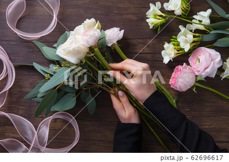 Florist at work: woman making fashion modern bouquet of different flowers on wooden background 62696617