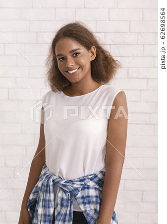 Portrait of smiling young girl over white brick wall 62698564