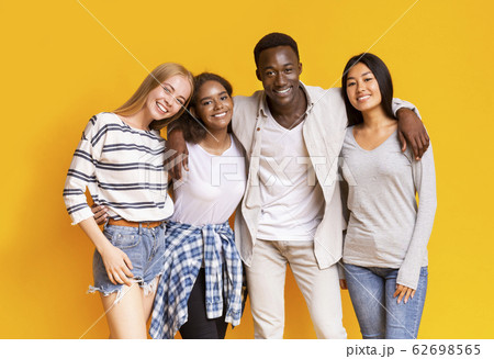 Positive multiethnic teenagers posing over yellow background 62698565