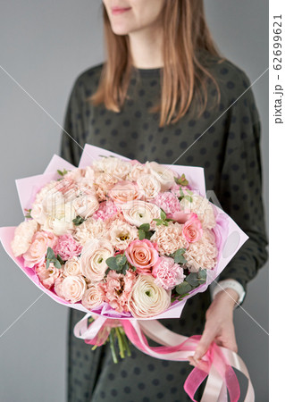European floral shop. Beautiful bouquet of mixed flowers in womans hands. the work of the florist at a flower shop. Delivery fresh cut flower. European floral shop. Beautiful bouquet of mixed flowers in womans hands. the work of the florist at a flower shop. Delivery fresh cut flower. 62699621