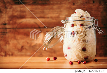 Fermented cabbage with cranberry in glass jar over wooden background. Probiotics food concept. Preserved vegetarian diet, homemade fermentation. Banner with copy space 62702123