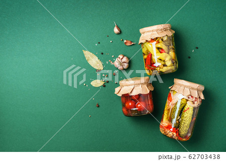 Сucumber, squash and tomatoes pickling and canning into glass jars. Ingredients for vegetables preserving. Healthy fermented food concept. Top view. Copy space. Сucumber, squash and tomatoes pickling and canning into glass jars. Ingredients for vegetables preserving. Healthy fermented food concept. Top view. Copy space. 62703438
