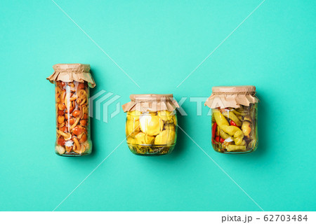 Canned and preserved vegetables in glass jars over yellow background. Top view. Flat lay. Copy space. 62703484