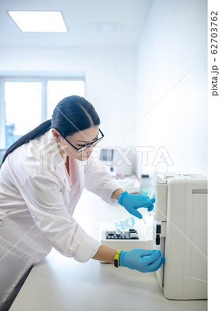 Technician in blue gloves switching on the centrifuge 62703762