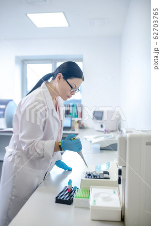 Technician in blue gloves pouring blood sample into the test tube 62703765
