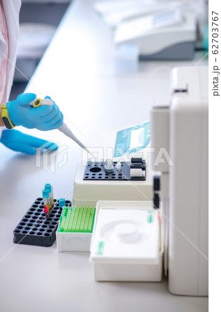 Technician in blue gloves holding pipette in hand 62703767