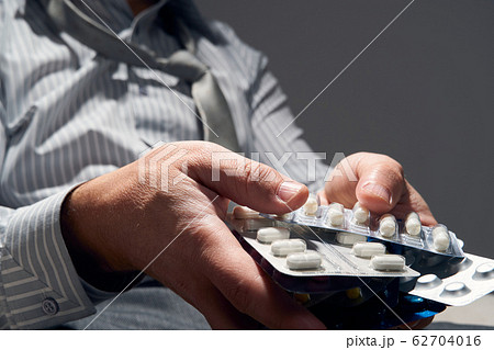 businessman with a pill, hands close view - 62704016