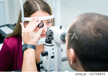 Attentive optometrist examining female patient in ophthalmology clinic 62708805