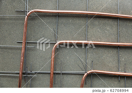 Bent new copper pipes laying on concrete floor 62708994