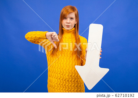 girl holds down arrow of paper and shows dislike on blue background girl holds down arrow of paper and shows dislike on blue background 62710192