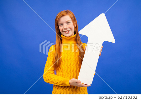 joyful girl holding an arrow out of paper with an upward direction on a blue background joyful girl holding an arrow out of paper with an upward direction on a blue background 62710302