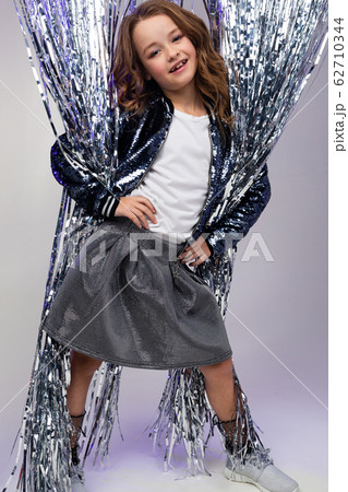 full-length photo of a stylish teenage girl in a festive dress among suspended tinsel in the form of full-length photo of a stylish teenage girl in a festive dress among suspended tinsel in the form of 62710344