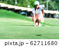 Young professional female golf player crouching and study the green before putting shot,she does exercise for relax time 62711680