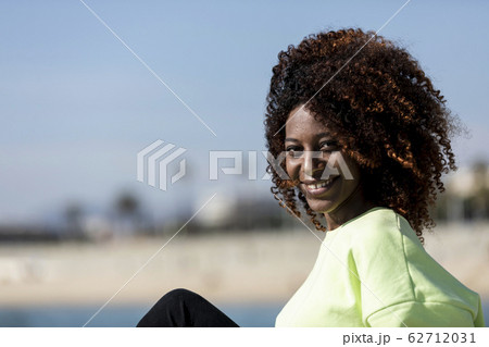 Beautiful afro american woman sitting on shore in 62712031